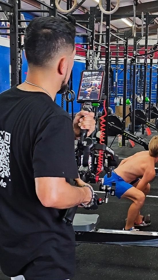 A videographer filming an athlete training in a gym, using a gimbal-mounted camera.