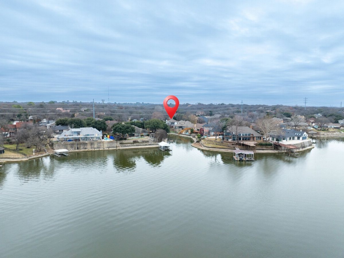 Aerial view of a lake surrounded by houses under an open sky.